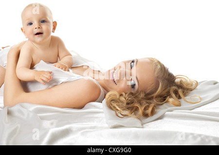 Hübsches Baby Sit-on-Mom im seidenen Bett Stockfoto