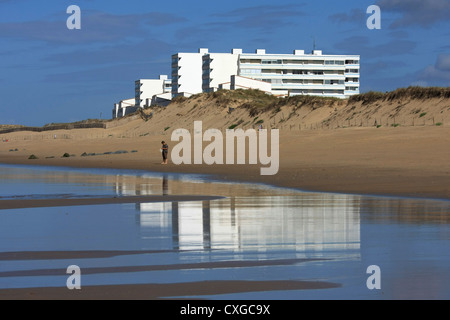 Einsame Gestalt am Strand mit einer großen modernen Apartment im Hintergrund Stockfoto