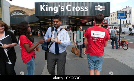 Red Cross Charity Arbeiter fundraising Gespräch mit einem Geschäftsmann Spenden sammeln auf der Straße vor dem Bahnhof King's Cross in London UK KATHY DEWITT Stockfoto