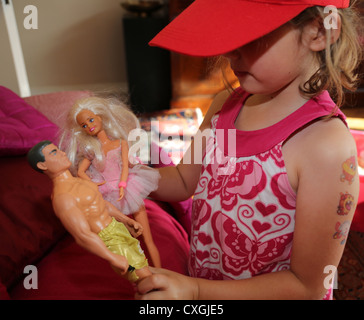 Junges Mädchen mit Wasser Transfer Tätowierungen auf ihren Arm und England-Baseball-Cap mit Puppen spielen Stockfoto