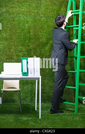 Mann, Klettern die Leiter neben dem Schreibtisch Stockfoto