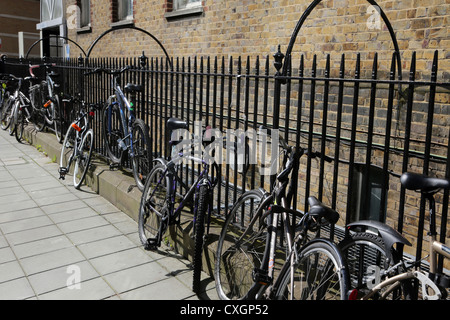 London England Fahrräder an Eisengeländern gesichert Stockfoto