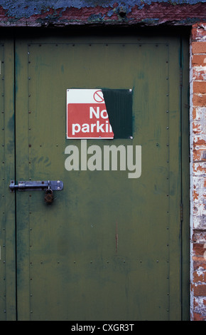 Verstärkte Sicherheits-Tür verschraubt und verschloss aber benötigen Malerei mit Zeichen die Hälfte abgerissen besagt, No Parking Stockfoto