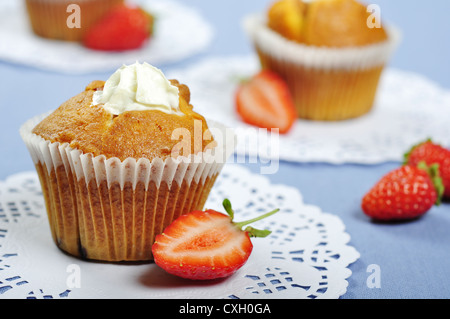 Muffins mit Erdbeeren und Schlagsahne auf Tischdecke Stockfoto