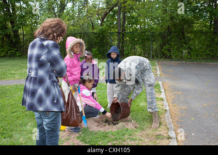 ROTC Freiwillige helfen Schülerinnen und Schüler einen Baum zu Pflanzen, am Tag des Baumes Stockfoto