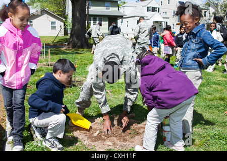 ROTC Freiwillige helfen Schülerinnen und Schüler einen Baum zu Pflanzen, am Tag des Baumes Stockfoto