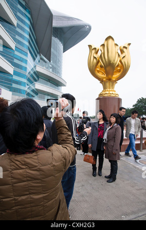 Chinesischer Touristen posieren für Fotos neben den Golden Bauhinia Skulptur, Hong Kong Stockfoto