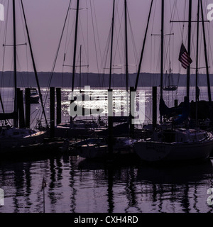 Angedockte Segelboote Silhouette gegen eine lila Himmel bei Sonnenaufgang. Sonnenlicht schimmert auf dem Wasser. Niantic East Lyme Connecticut USA Stockfoto