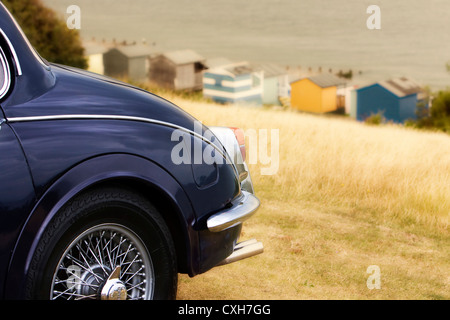 Jaguar Mk II, parkte auf dem Rasen an Spitze der Tankerton Pisten, Whitstable, Kent, England, UK mit Strandhütten und Meer im Hintergrund Stockfoto