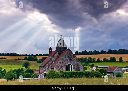 St. Huberts Church in Idsworth Hampshire mit Strahlen der Sonne durch die Wolken kommen aus dem Osten suchen Stockfoto