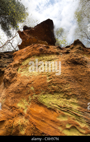 Greensand Ridge Sandstein Ablagerungen als unterschiedliche Schichten und satten orange Farben am Fuße eines einsamen Steilklippe Gesichts Stockfoto