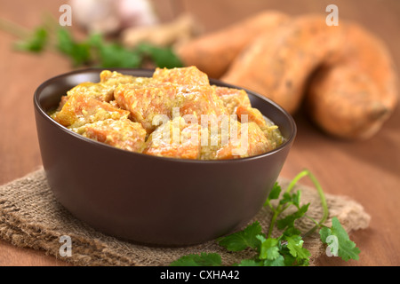 Schüssel mit vegetarischen Süßkartoffel-Kokos-Curry mit Zutaten in den Rücken Stockfoto