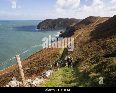 Wanderer zu Fuß unten trat Abschnitt der Insel Anglesey Coastal Path mit Blick entlang der zerklüfteten Küste in der Nähe von Cemaes ANGLESEY Wales UK Stockfoto