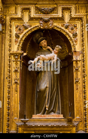 Eine alte historische Skulptur von Baby Jesus Christus und ein Mönch in goldenen verzierten Nische im Inneren der Kathedrale Mezquita in Córdoba, Spanien. Stockfoto