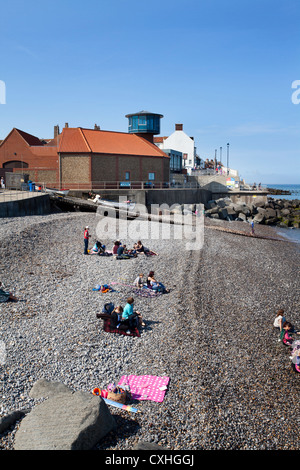 Leute sitzen auf den Kiesstrand an der Sheringham Norfolk in England Stockfoto