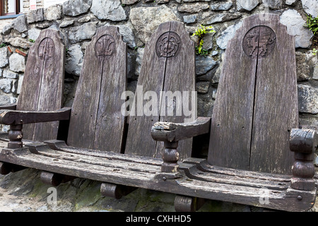 Antiken hölzernen Sitze draußen Pembroke Castle Eingang, Pembrokeshire, Wales, UK. Stockfoto