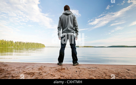 Ein Mann steht auf der Sand See Küste am Horizont Darsteller Stockfoto