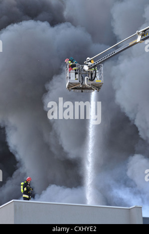 Feuerwehrleute löschen ein wütende Feuer in einem Lagerhaus. Stockfoto