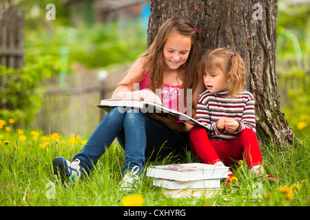 Kinder, die Lektüre des Buches im Sommerpark Stockfoto