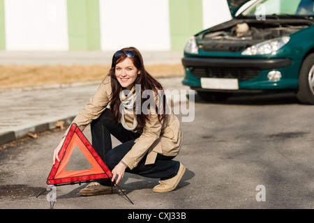 Frau, die Auto Aufschlüsselung Schild Warndreieck aufsetzen Stockfoto