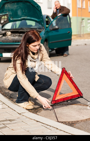 Frau putting Dreieck Zeichen für Auto Panne Problem Absturz Warnung Stockfoto