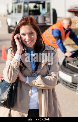 Frau am Handy nach Panne Probleme Problem Automechaniker Stockfoto