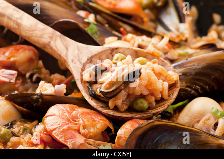 Meeresfrüchte-Paella mit Muscheln, Garnelen, Calmari und Holzlöffel als Closeup in einer Pfanne Stockfoto