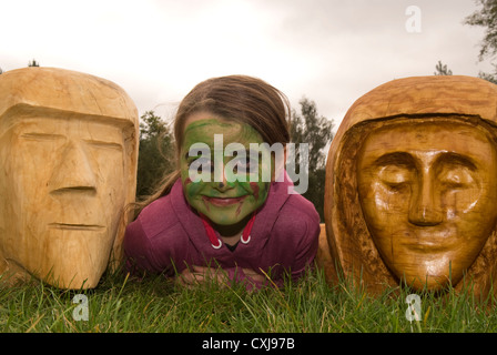 8 Jahre altes Mädchen Verlegung zwischen 2 Kettensäge Holzschnitzereien an eine Forstwirtschaft Kommission Discovery Day Stockfoto