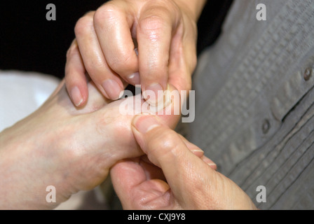 Reflexologin am Arbeitsplatz bei einer Veranstaltung von alternativen Therapien, Alton, Hampshire, UK. Stockfoto