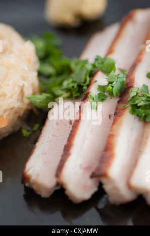 Traditionelle deutsche Küche, gebratenes Schweinefleisch mit Sauerkraut. Mit Senf und Petersilie serviert Stockfoto