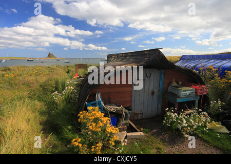 Umgedrehten Boote als Schuppen auf Lindisfarne, heilige Insel, mit der Burg im Hintergrund verwendet. Stockfoto