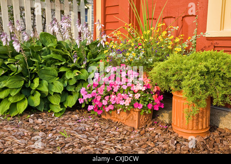 Pflanzer verwendet im Hause Sommergarten mit Impatiens, Wacholder und andere Blumen gefüllt. Stockfoto