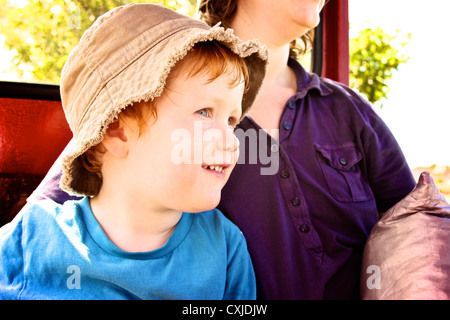 Der junge Sohn mit Mutter lächelt glücklich außerhalb Abenteuer Sonne Hut und Sommer Kleidung Stockfoto