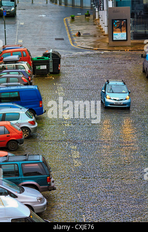 Auto mit Scheinwerfern auf Kopfsteinpflaster fahren entlang einem nassen Street, Edinburgh, Schottland Stockfoto