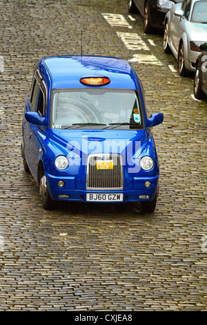 London Taxi fahren entlang einer nassen gepflasterten Straße, Edinburgh, Schottland Stockfoto