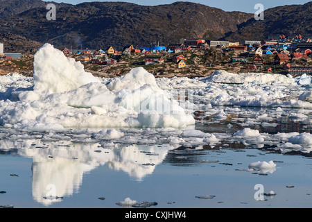 Bunte Gebäude des Ilulissat sitzen am Rande der Stadt Eis verstopft Hafen und spiegeln sich im Wasser zwischen den Eis-Bits. Stockfoto