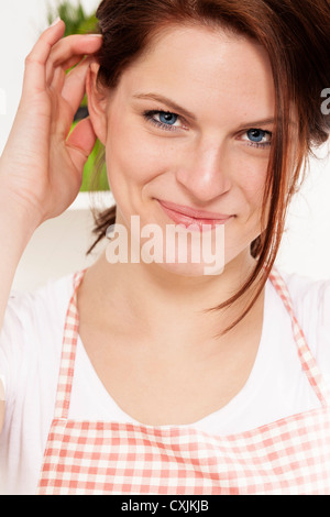 Porträt einer jungen Frau trägt eine Schürze in ihrer Küche Stockfoto