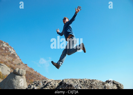 Mann springt auf den Felsen Stockfoto