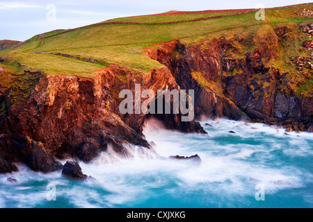 Wellen gegen die Klippen mit Höhle, Bürzel Punkt, Cornwall, England Stockfoto