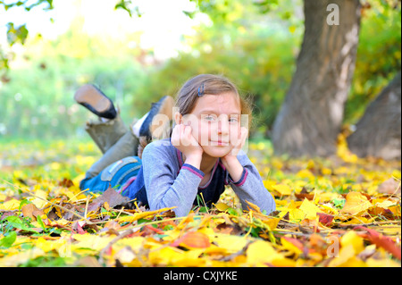 kleines Mädchen legt auf den Blättern Stockfoto