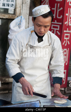 Koch bereitet am frühen Morgen Snacks auf den Straßen von Peking Stockfoto