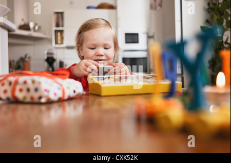 Kleines Mädchen sitzt am Tisch Öffnung Geschenke Stockfoto