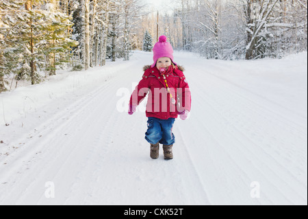 Porträt von kleinen Mädchen Winter Walking Down Road Stockfoto