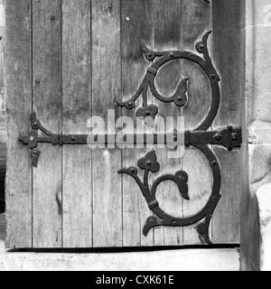 Eine alte Holztür in ein Gebäude Trinity Street in Cambridge. Es hat einen schmiedeeisernen, großen und dekorativen schwarzen Scharnier. Stockfoto