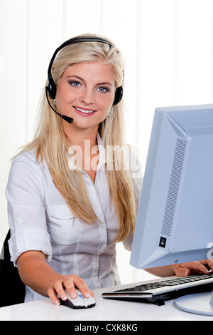 Frau am Computer mit Kopfhörer und Hotline Stockfoto