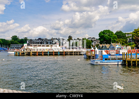 Die Sonne scheint auf die vielen Piers von Bowness Bay mit einem Ausflugsschiff entlang um Passagiere für eine Kreuzfahrt rund um den See Stockfoto