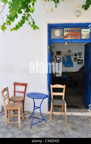 Drei Stühle und ein kleiner blauer Tisch vor einem winzigen Café mit einem Zimmer, das von einer älteren Dame in Pano Elounda, Kreta, den griechischen Inseln, Griechenland und Europa geführt wird Stockfoto