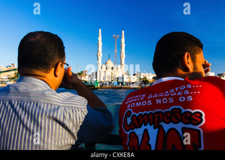 Ägyptische Männer auf der kostenlosen Fähre über den Suez-Kanal von Port Said, Port Fuad mit großen Port Fuad Moschee in Backgroung. Ägypten Stockfoto