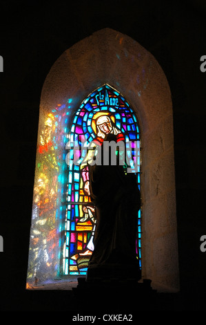Glasfenster mit Statue vor und Reflexion an Wand. 12.-13. Jahrhundert Kirche Montrol-Senard. Stockfoto