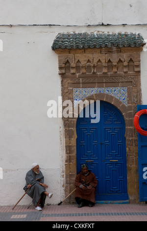 Zwei ältere marokkanische Männer sitzen mit Gehstock auf Hockern in Straße in Essaouira, Marokko Stockfoto